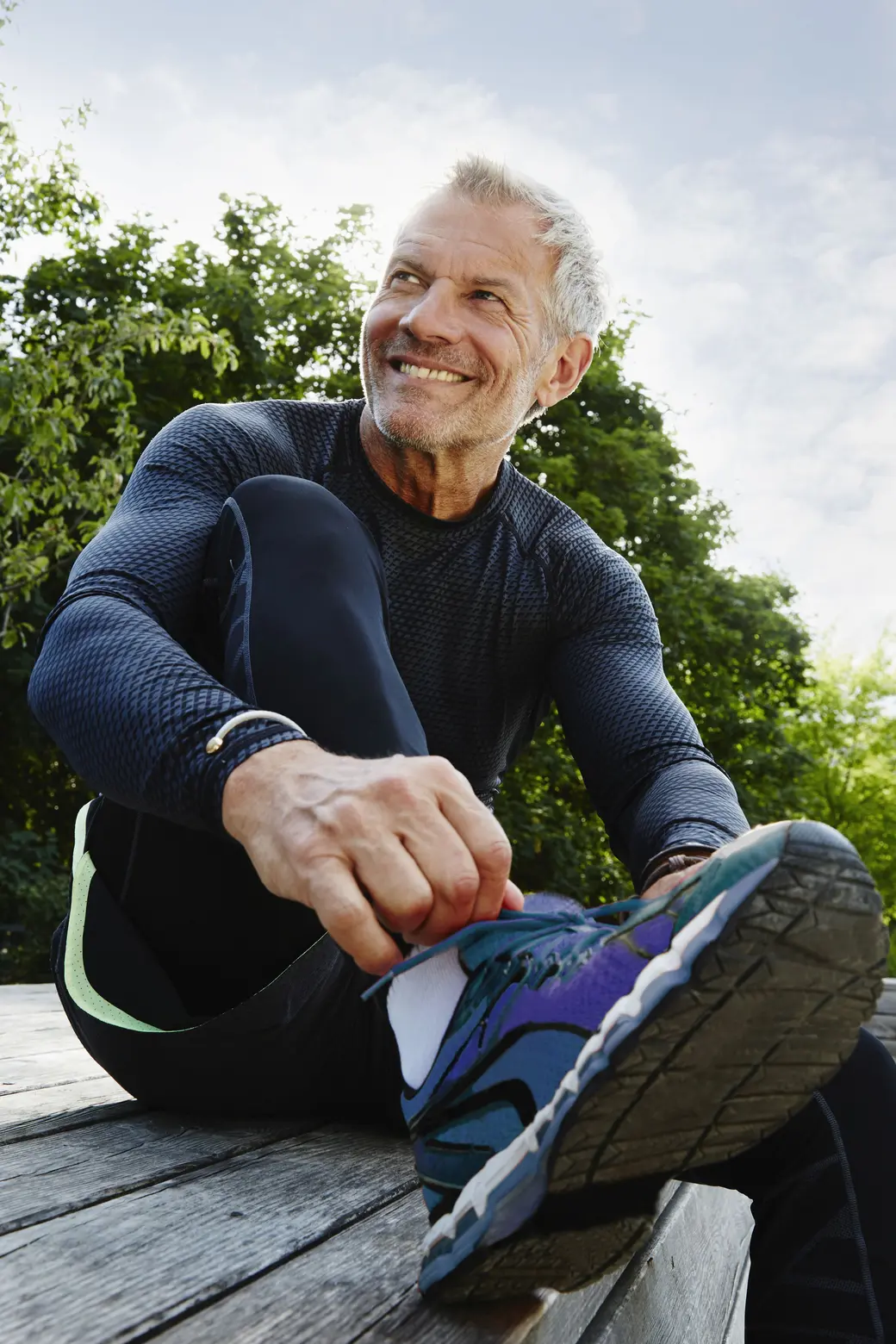 Мъж със спортни дрехи, който си връзва маратонките