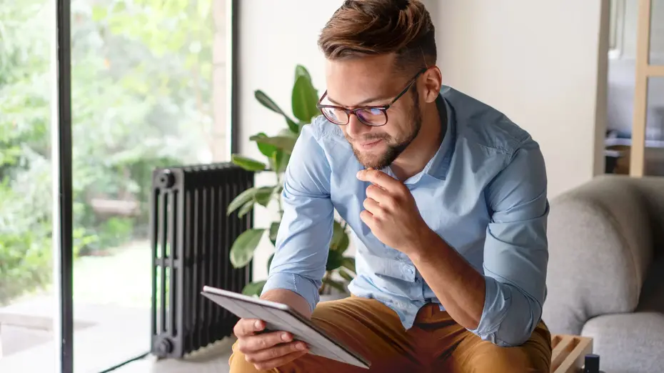 Млад мъж с очила чете от таблет