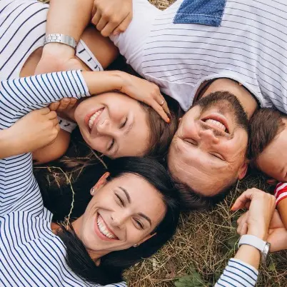 Семейство, което е легнало на полянка и се усмихват